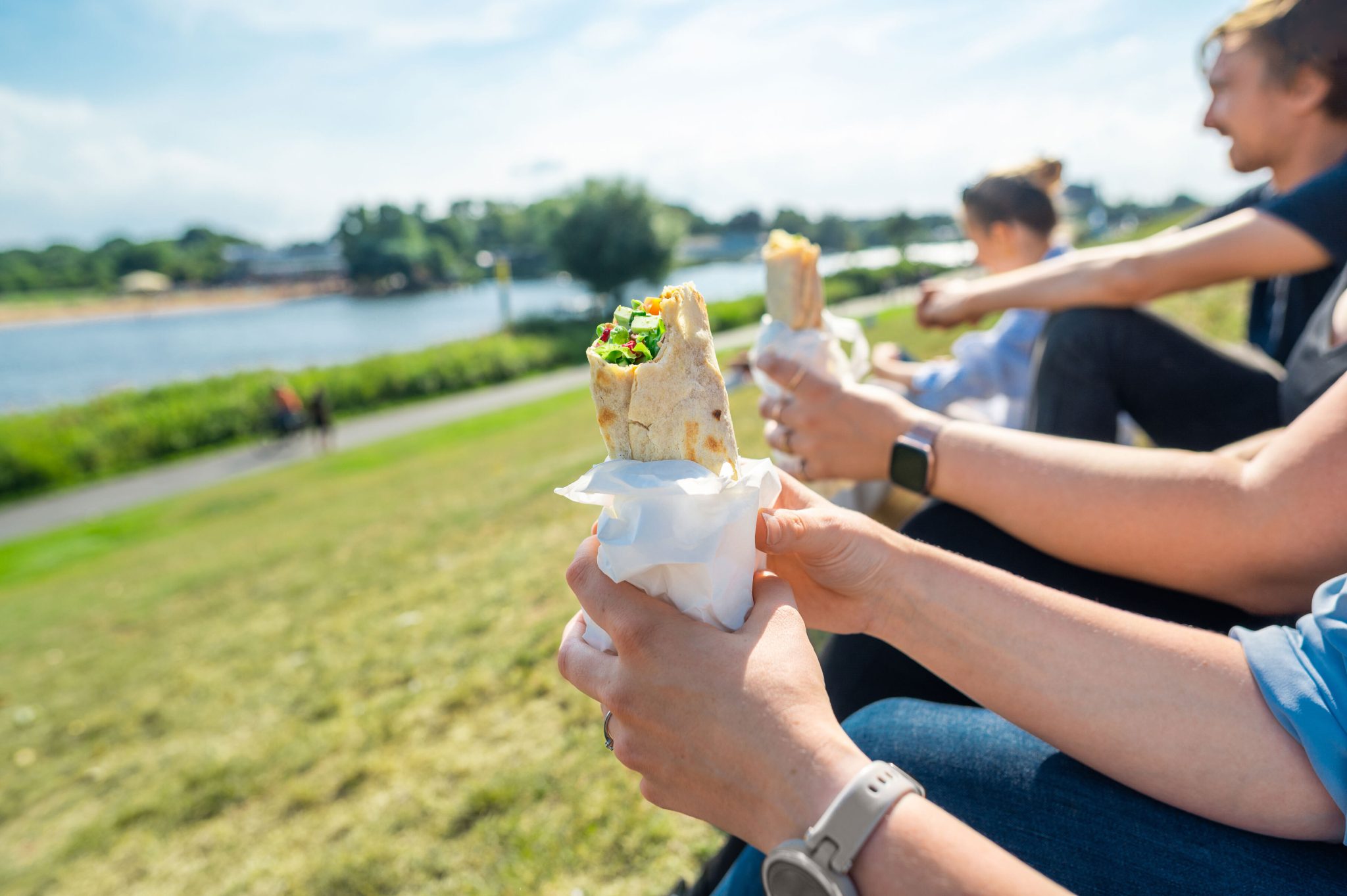 Junge Menschen sitzen auf dem Deich und haben jeweils einen Rollo in der Hand.